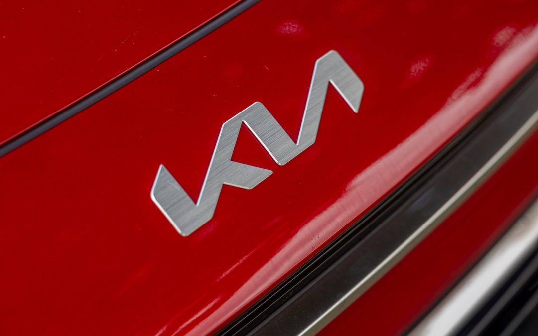 Kia logo close-up on red vehicle exterior